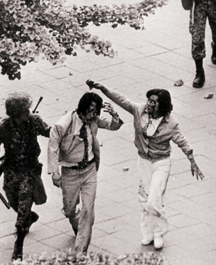 젊은 남녀가 금남로2가를 지나다 공수부대가 휘두른 곤봉에 머리를 맞아 피흘린 채 끌려가고 있다.